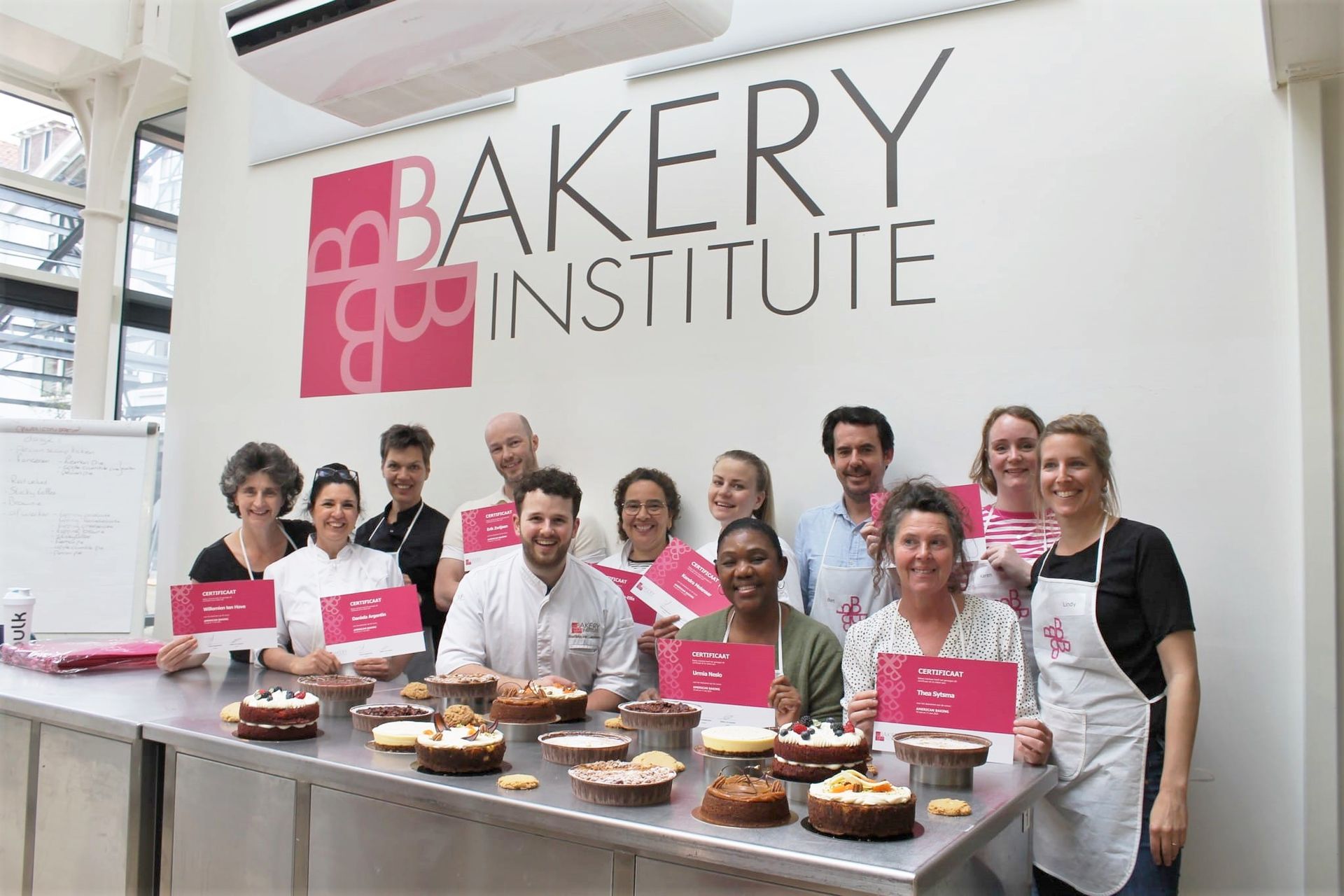 Een groep mensen van het Bakkerijinstituut poseert met gebak
