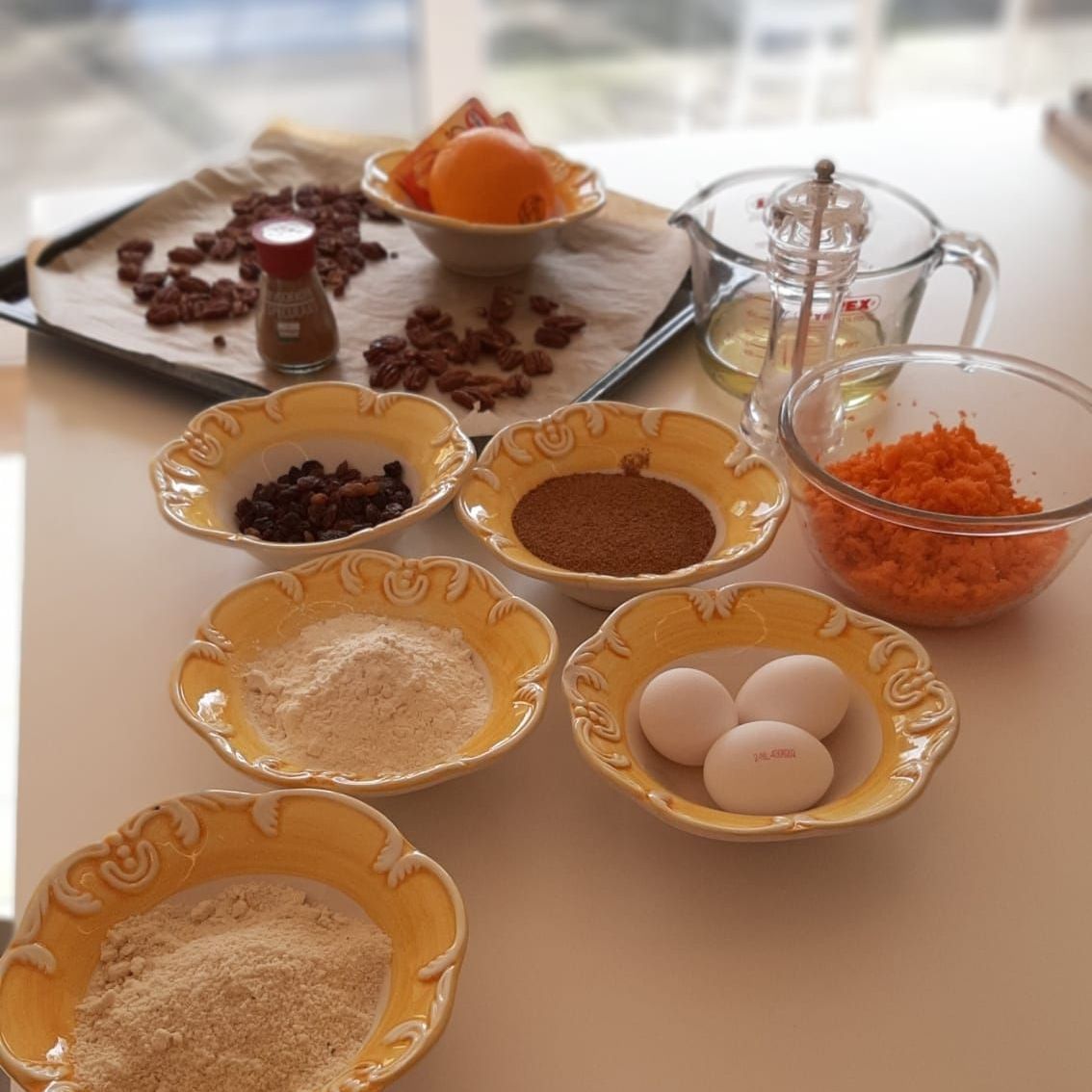 Ingrediënten voor worteltaart: bloem, specerijen, eieren, wortels, pecannoten en rozijnen