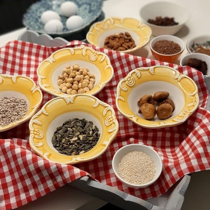 Diverse ingrediënten in gele kommen en eieren op een geruite doek om te bakken.