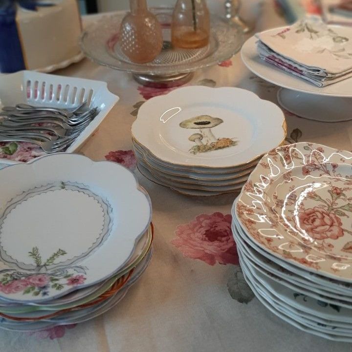 Tafel gedekt met bloemenborden, etagères, bestek en vintage decoraties.