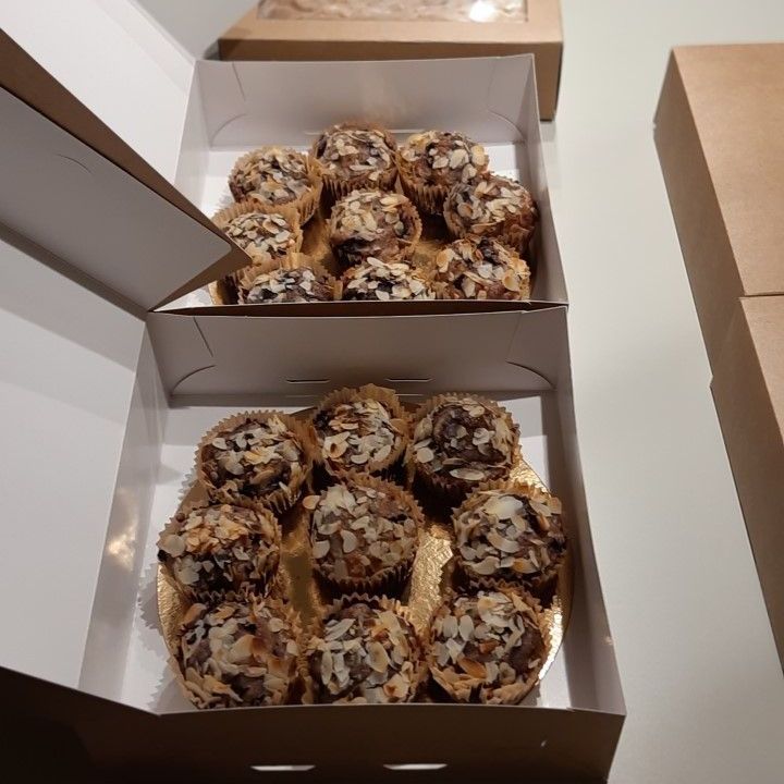 Twee doosjes chocoladetruffels, afgewerkt met amandelschaafsel, in witte doosjes.