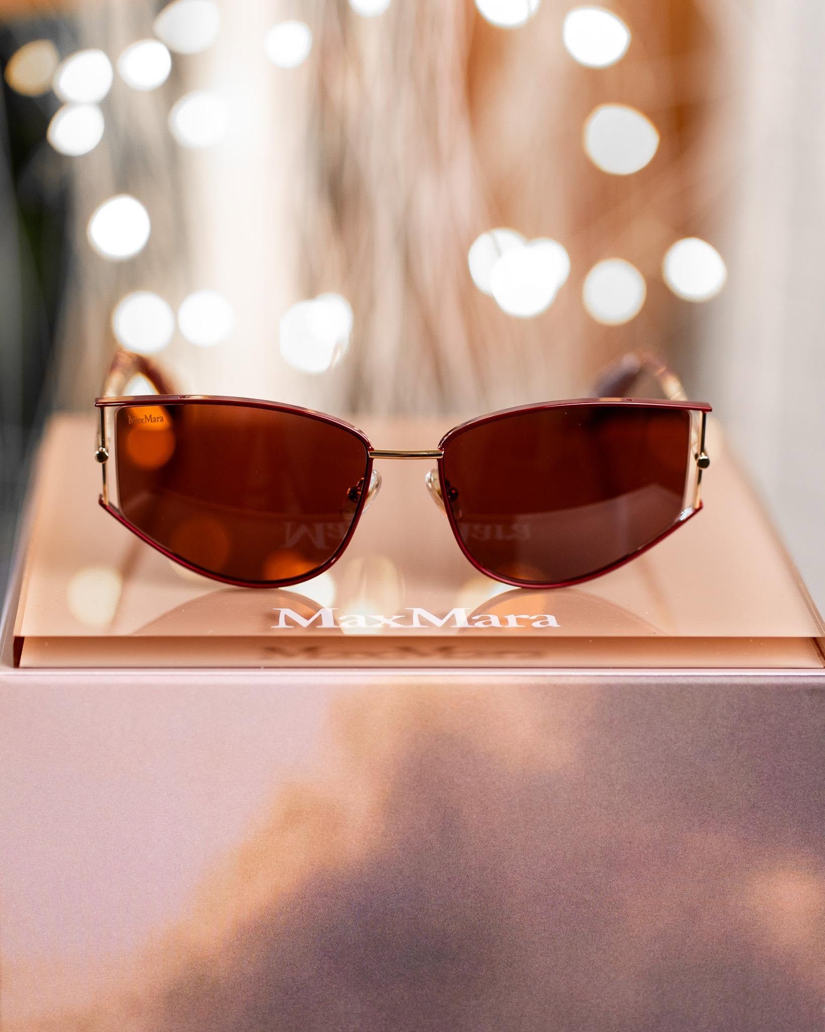Brown sunglasses on a display stand with blurred lights in the background