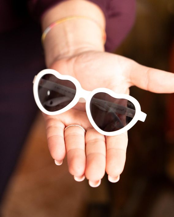 White sunglasses resting on an open hand.