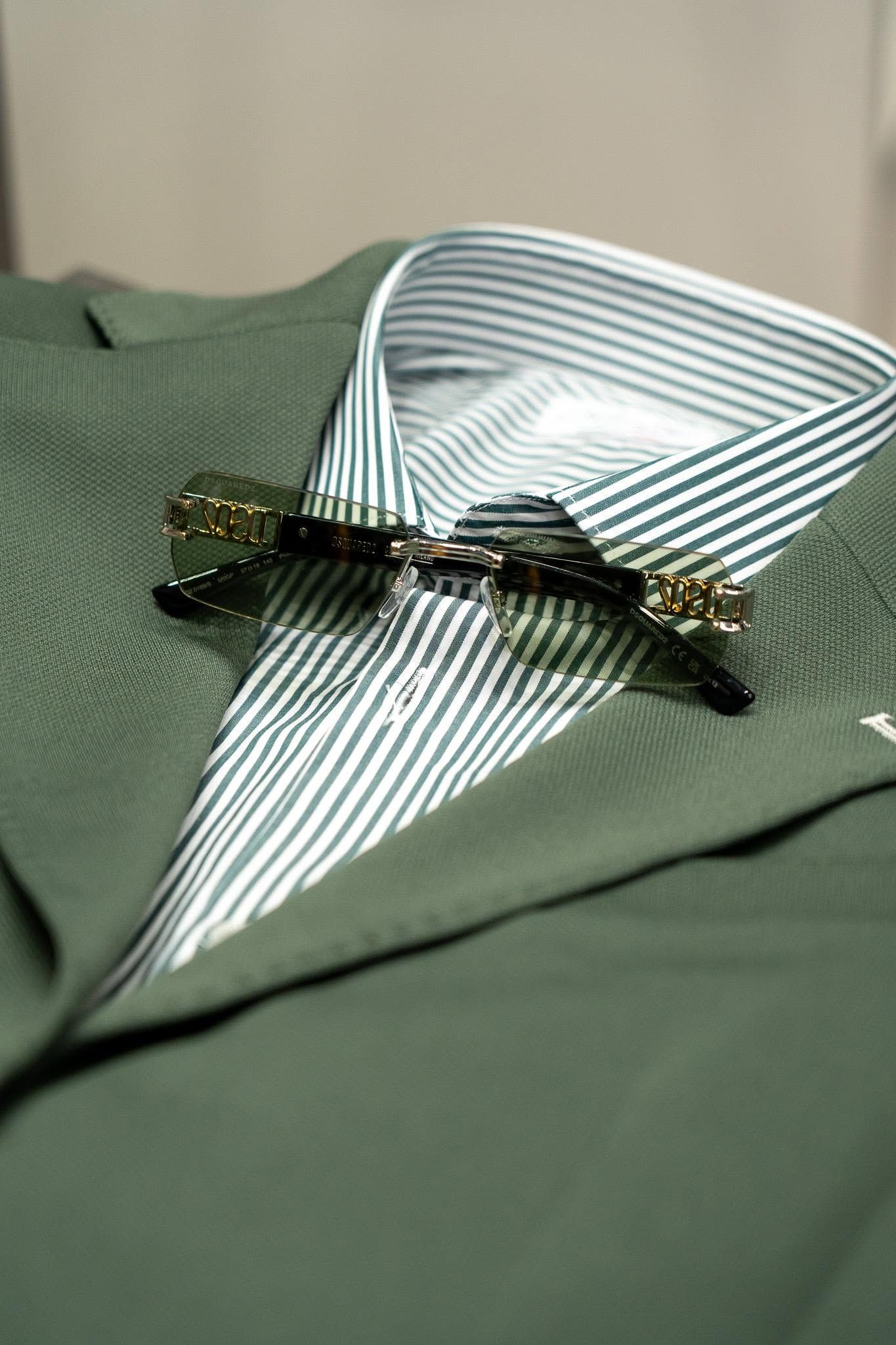 Striped green bow tie on a green fabric surface with a black clip.