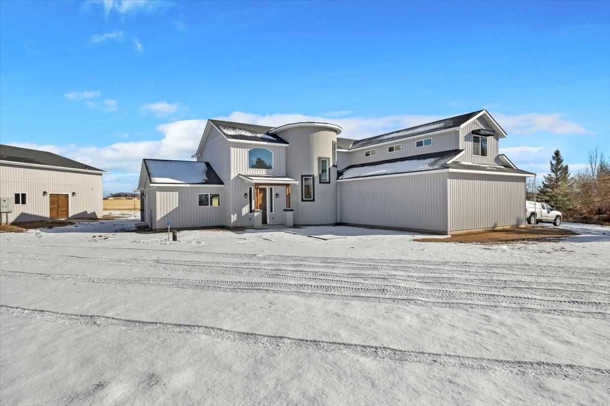 Light gray house with snow-covered ground and a clear blue sky.