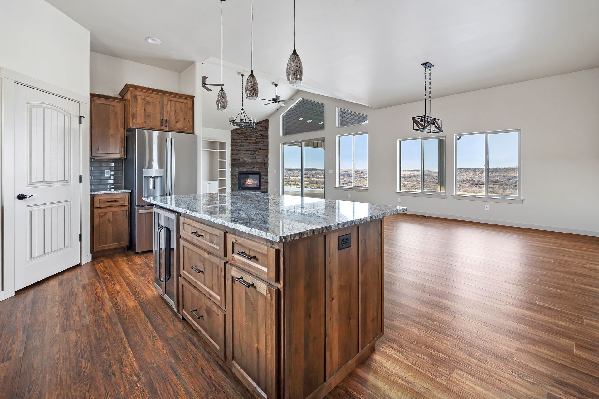 Kitchen with island, wood cabinets, stainless steel appliances, and large windows with a scenic view.