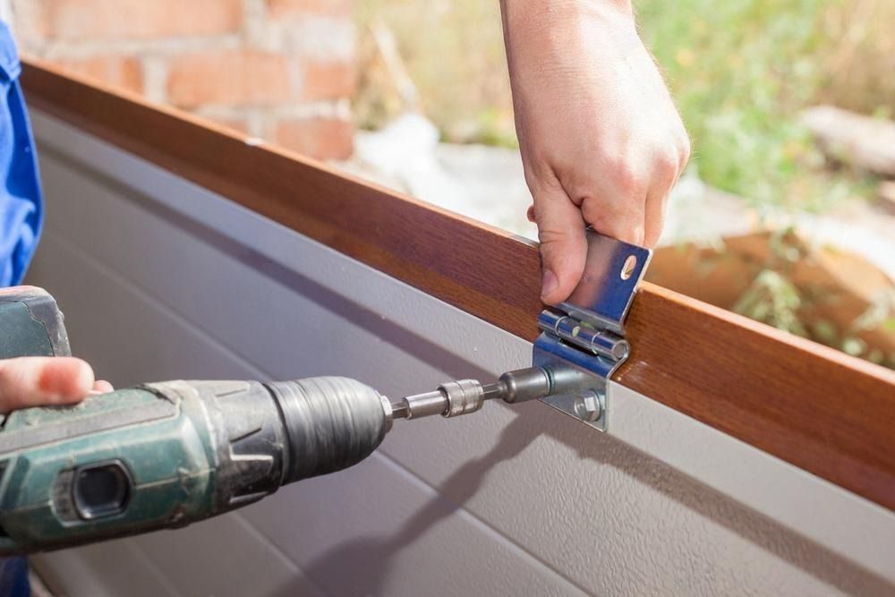 A man is using a drill to install a garage door.