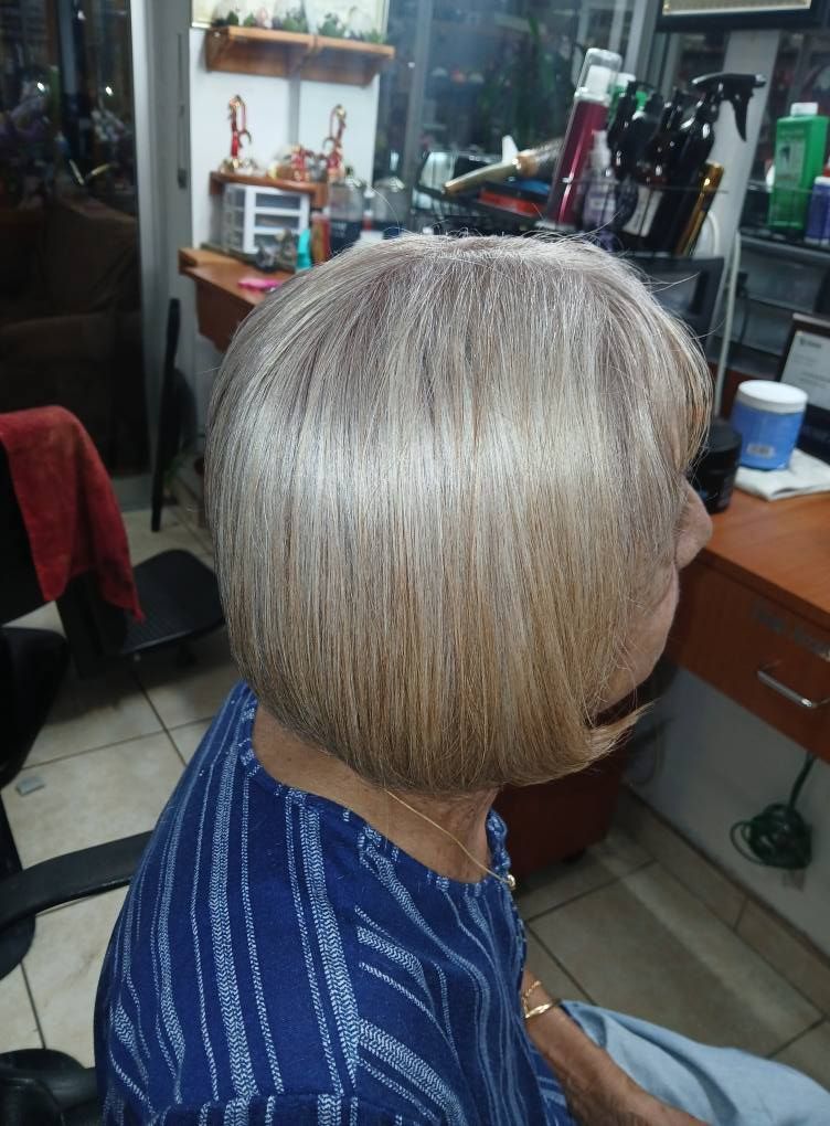 A woman with a short, layered, blonde bob haircut sits in a hair salon.