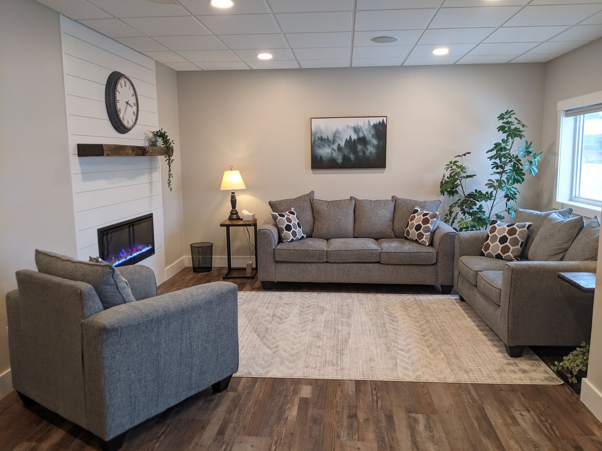 Living room with gray furniture, fireplace, rug, and artwork.