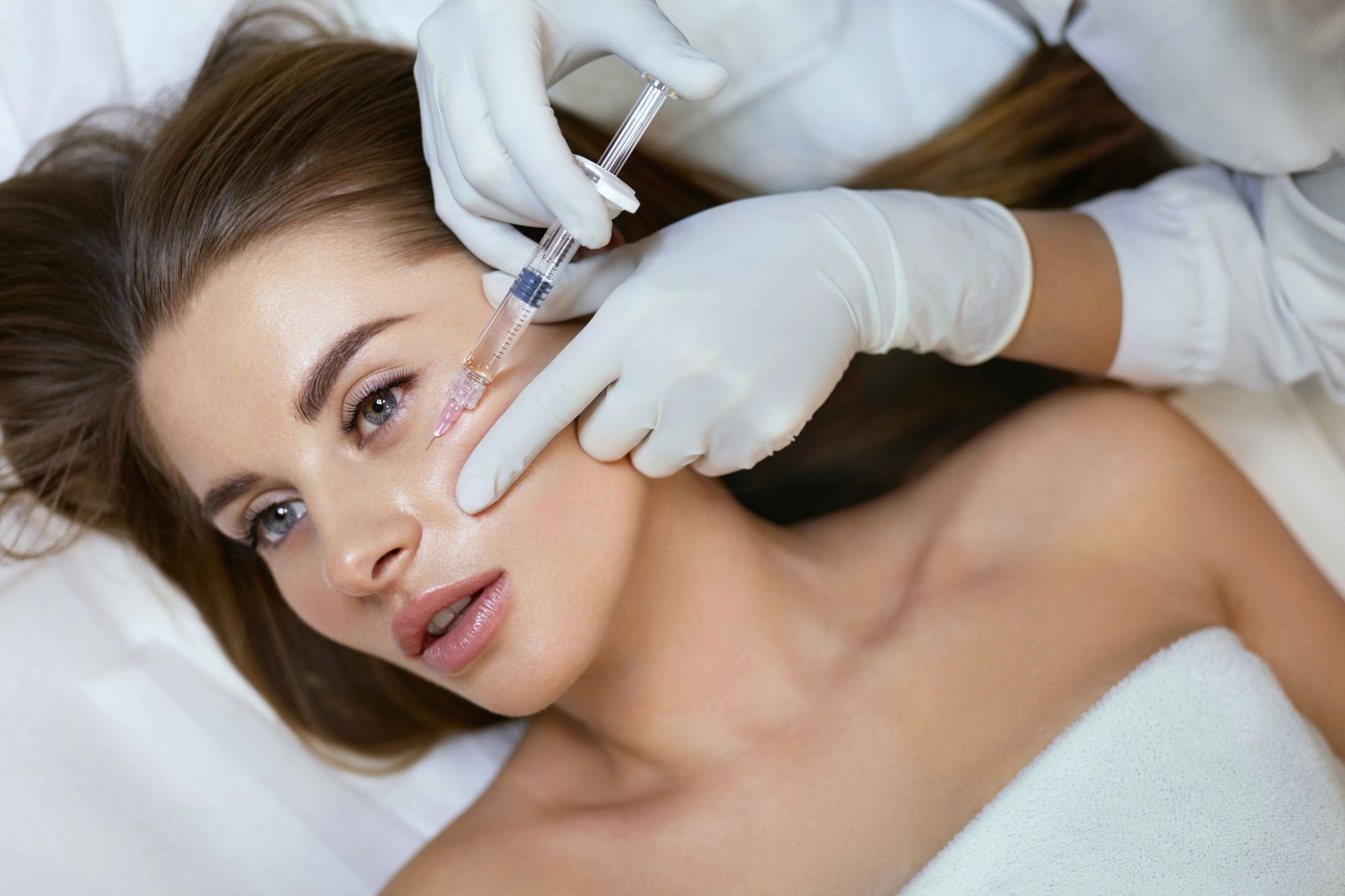 A woman is getting a botox injection in her face.