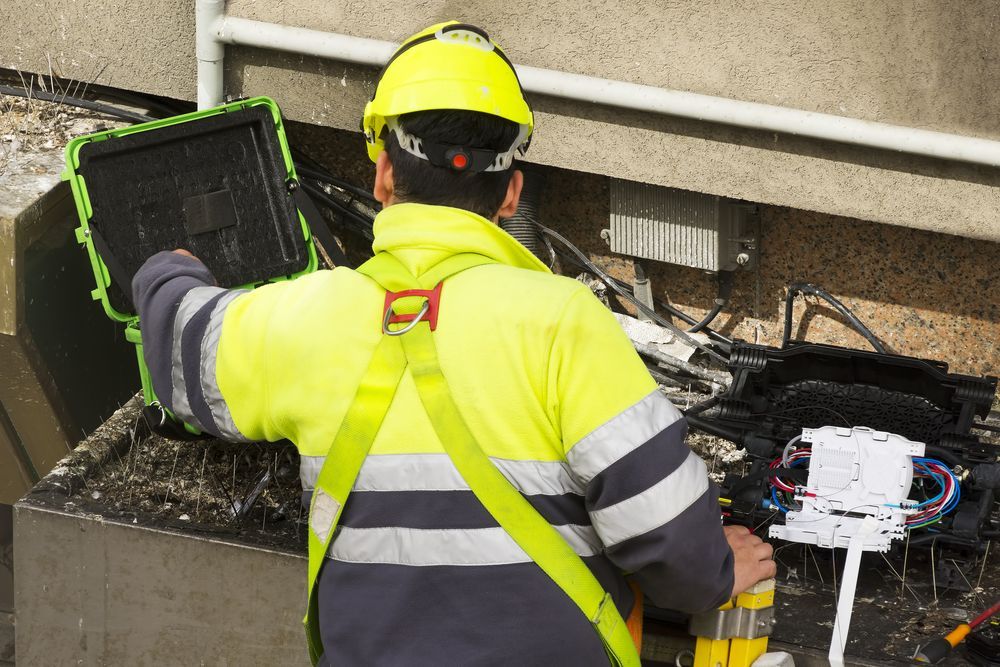 A Construction Worker Is Looking At A Tablet In A Building — Country to Coast Cabling in Kawana, QLD