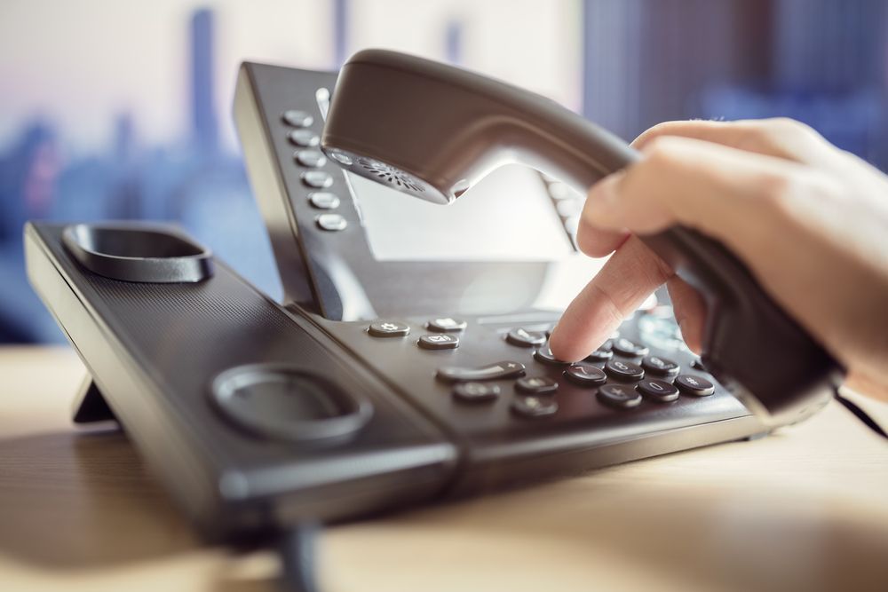 A Person Is Pressing A Button On A Telephone — Country to Coast Cabling in Kawana, QLD