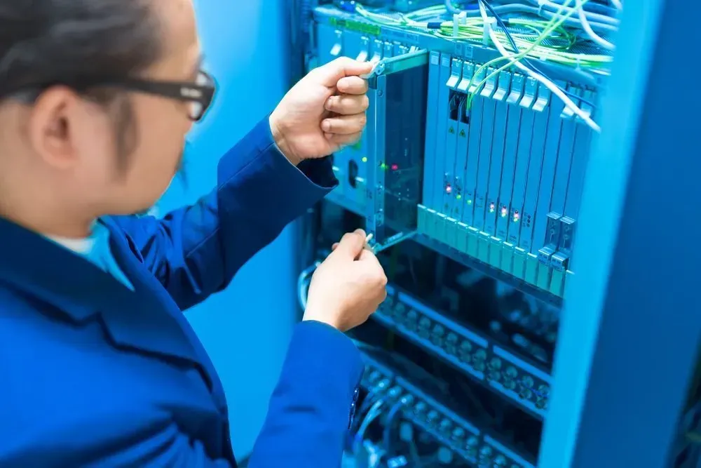 A man in a blue jacket is working on a server — Country to Coast Cabling in Kawana, QLD