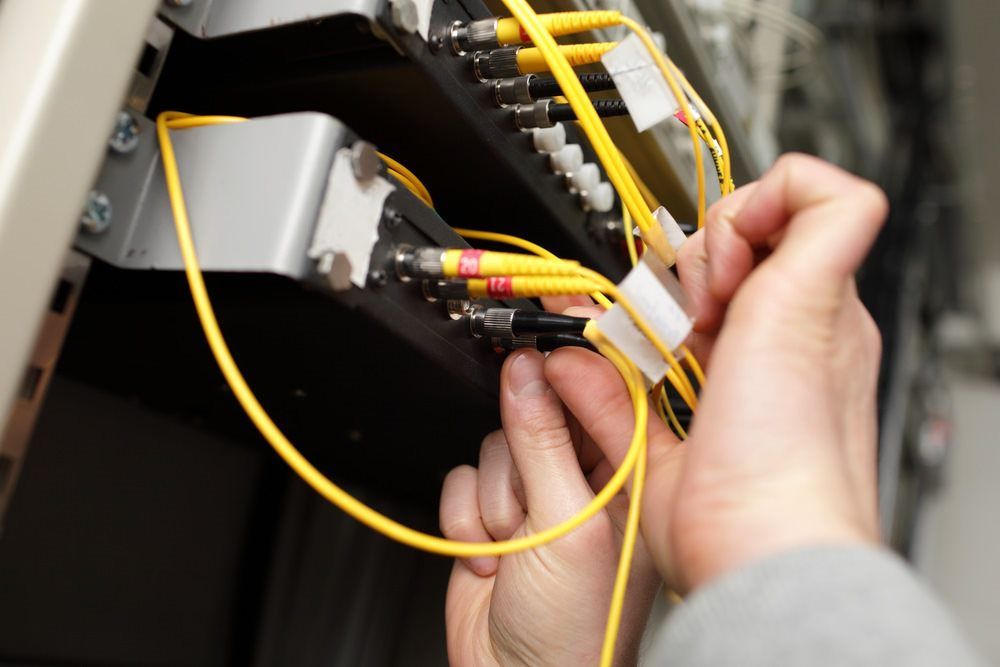 A Person Is Holding A Yellow Cable In Their Hands — Country to Coast Cabling in Kawana, QLD