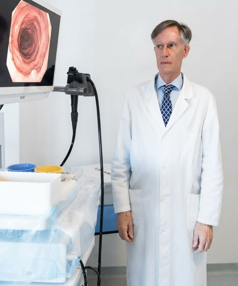 Un medico in camice bianco è in piedi accanto a un monitor medico che mostra un'immagine di scansione circolare.