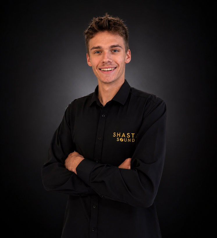 Smiling person in a black shirt with arms crossed against a dark background