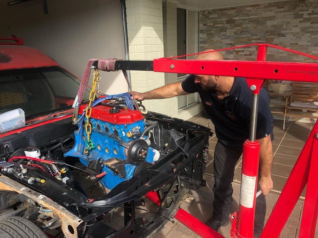 A Man Is Working On A Car Engine In A Garage — SG Mobile Mechanic In Newcastle, NSW