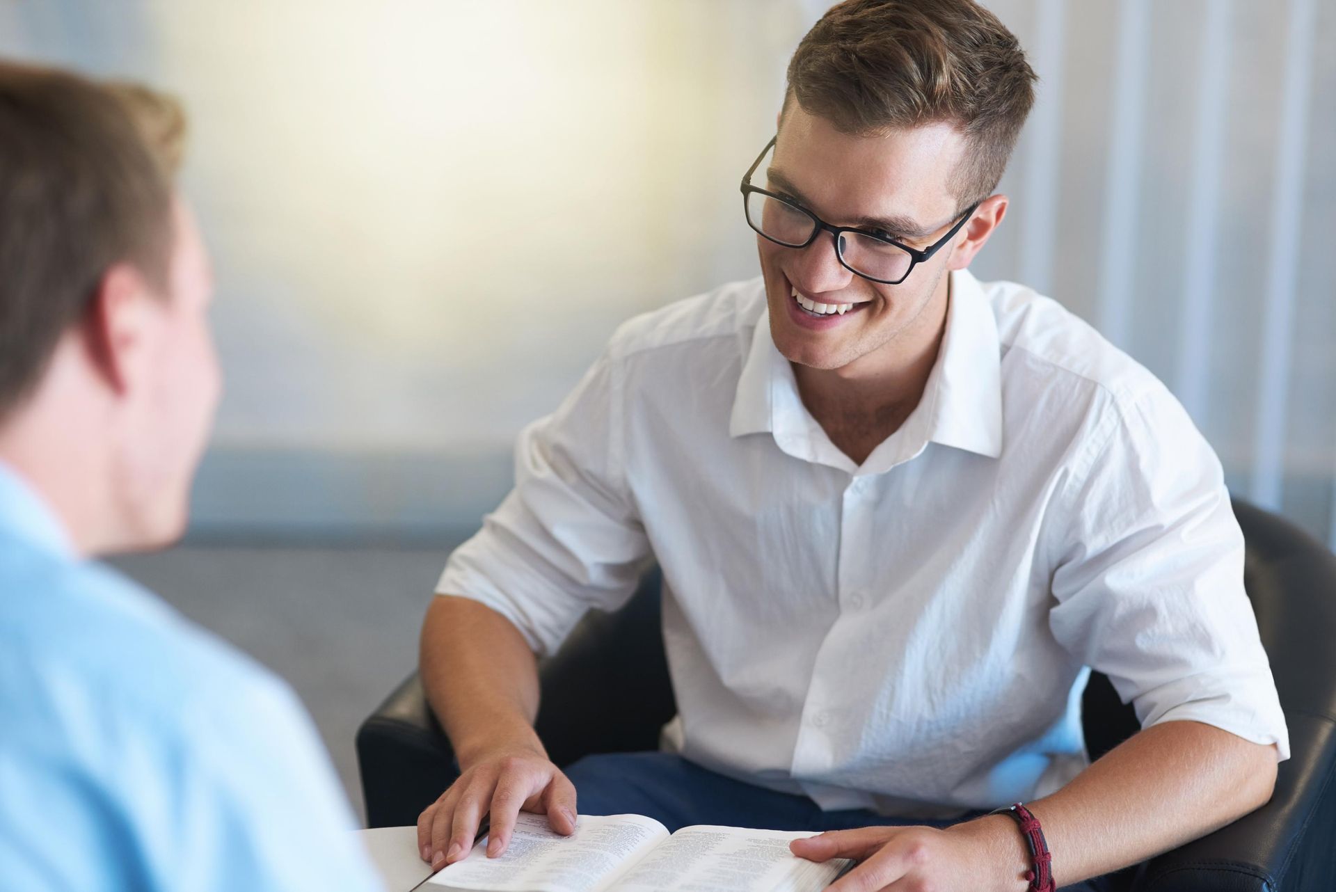 Two people in a meeting, one smiling and reviewing documents across a table.