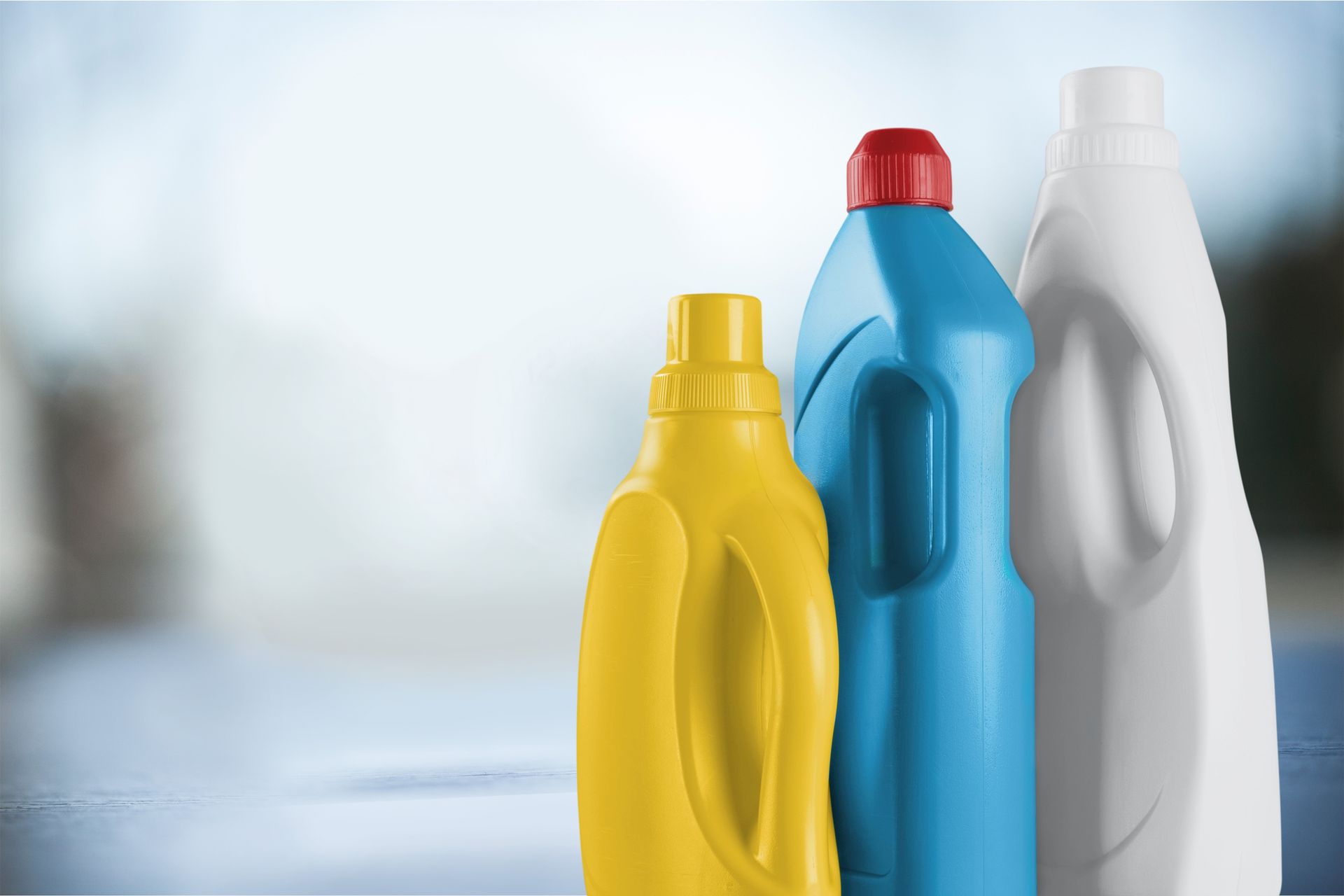 Hay tres botellas de detergente para ropa sobre una mesa.