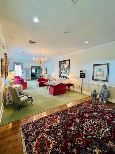 Spacious living room with colorful furniture, chandelier, framed art, and patterned rug