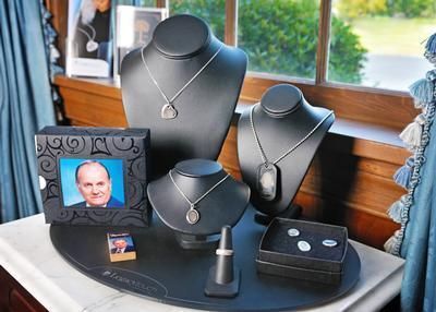Jewelry display with black necklace stands, earrings, and framed portrait on a round table by a window
