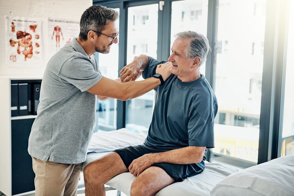 Caregiver checking a seated patient’s neck with a stethoscope in a bright medical room