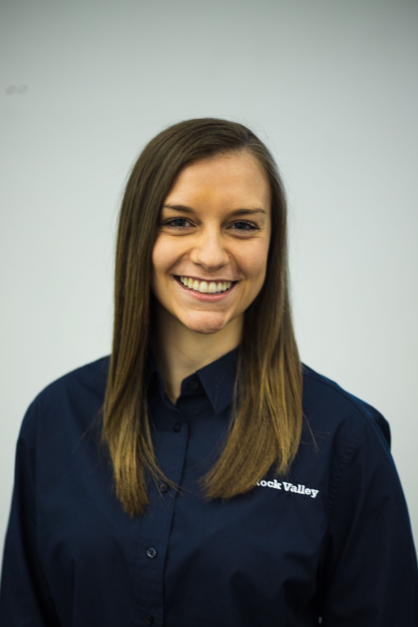 Smiling person in a navy shirt against a light gray background