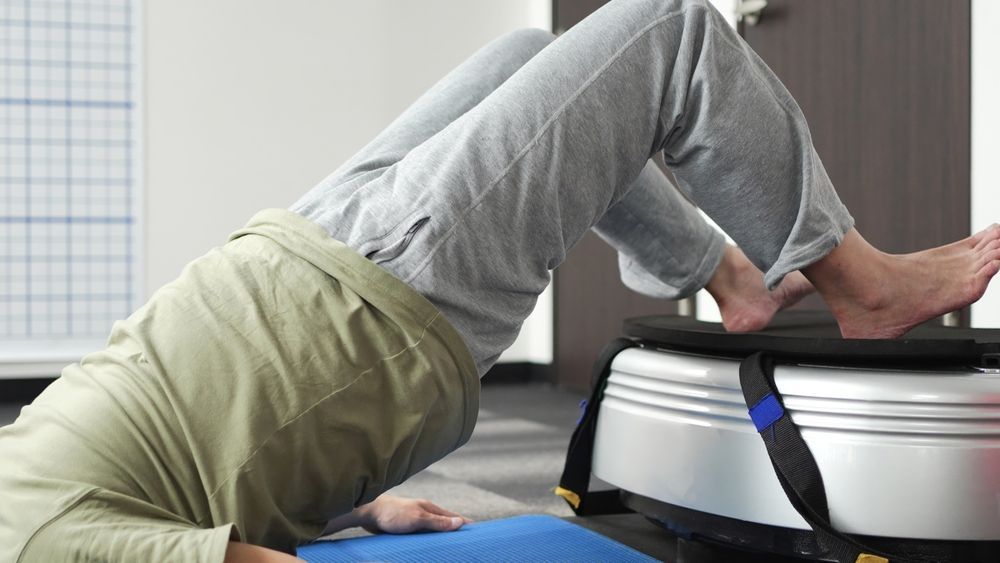 Person doing a bridge exercise with feet on a bench in a gym setting.