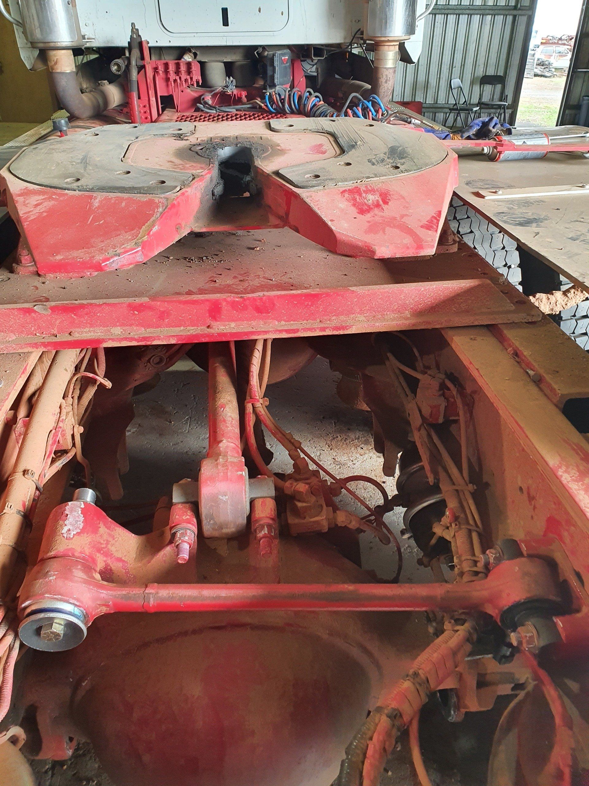 Red semi-truck chassis with the fifth wheel and suspension visible.