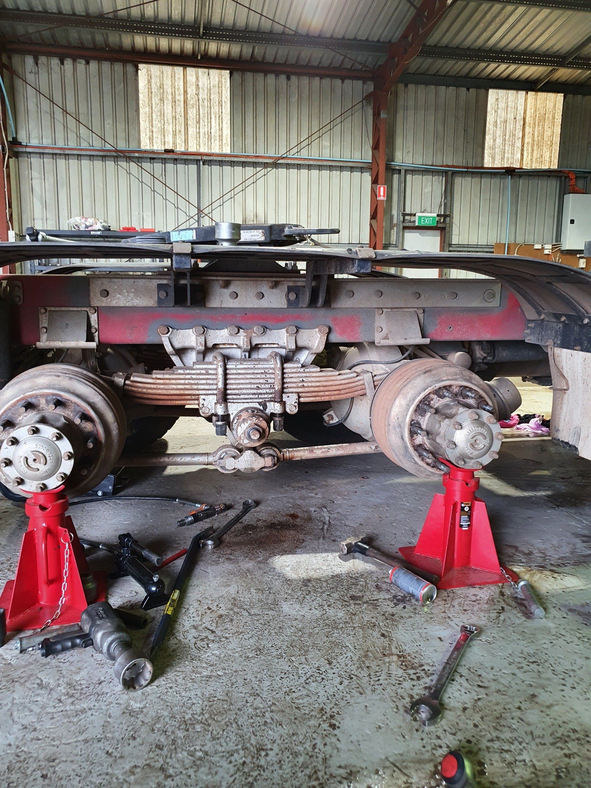 Truck chassis on jacks in a garage, wheels removed.