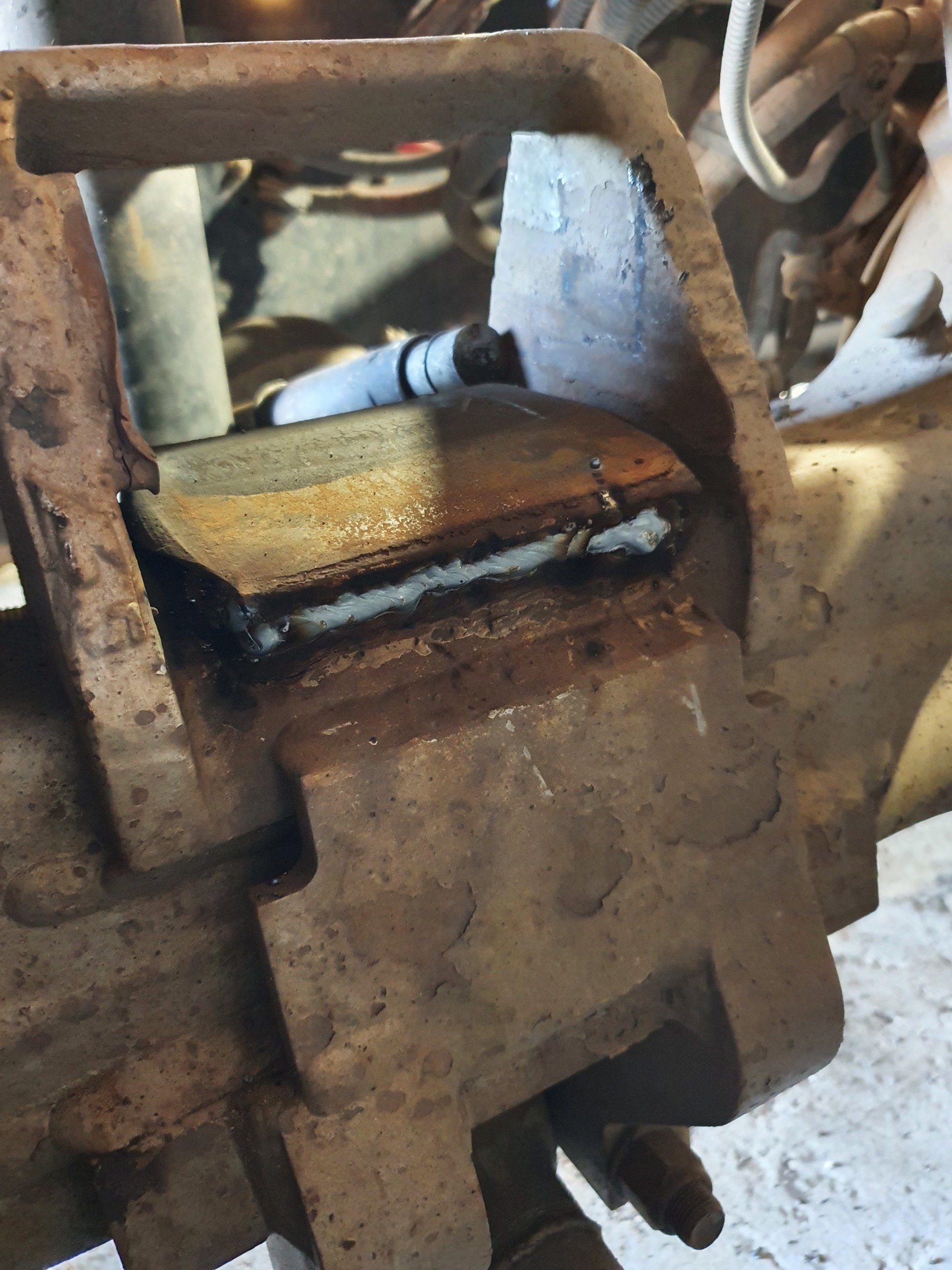 Rusty, welded metal component on a vehicle axle.