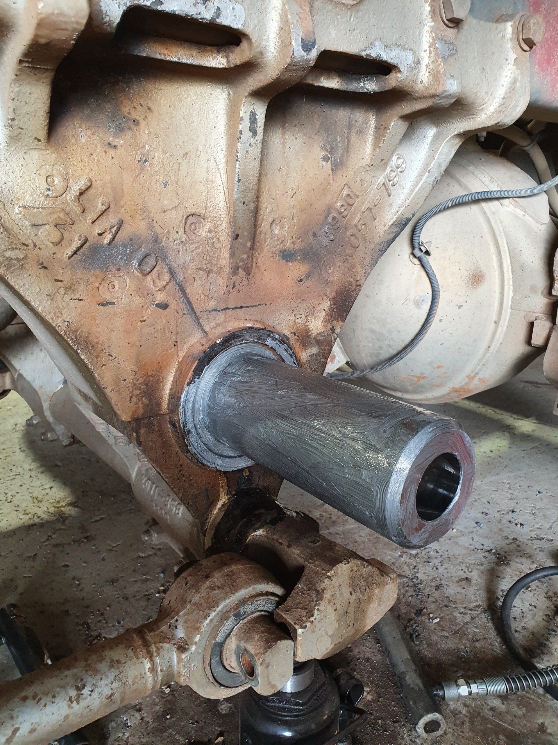 A close-up of a rusty metal vehicle component with a cylindrical tube extending outwards.
