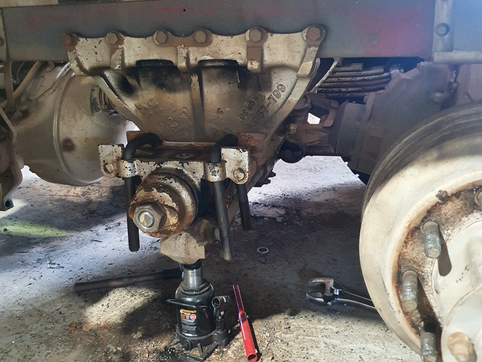 Truck chassis with a jack under the axle; repair work in progress.