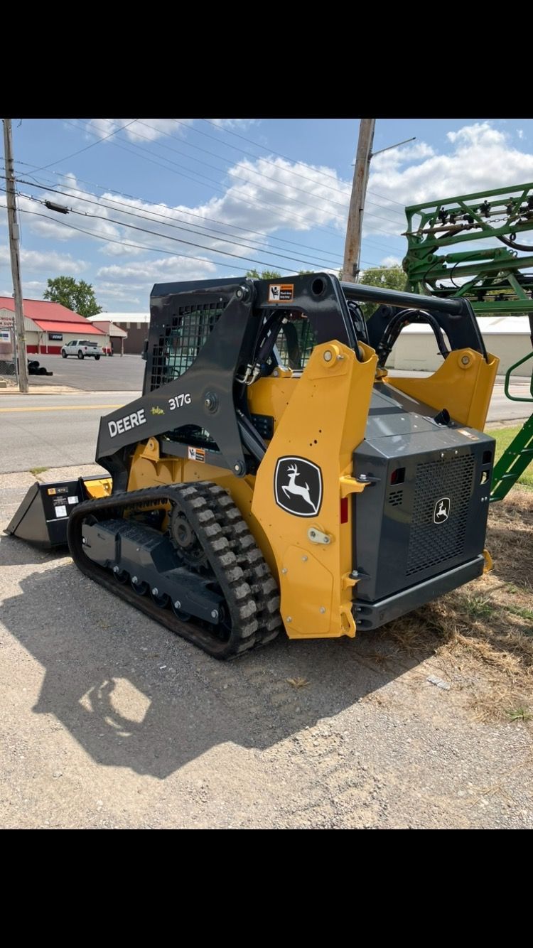 A john deere skid steer loader is parked on the side of the road.