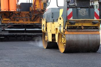 Apisonadora compactando asfalto fresco en una obra vial.