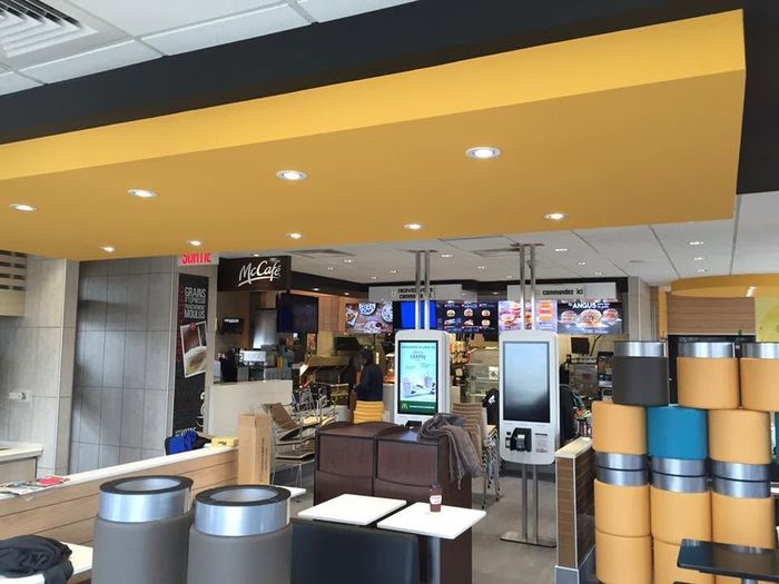 Comptoir de café d'aéroport avec panneaux de menu, sièges et panneaux de plafond jaunes