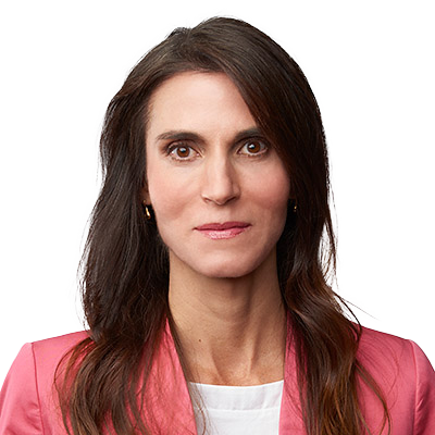 Portrait of a woman with dark hair wearing a pink blazer against a white background