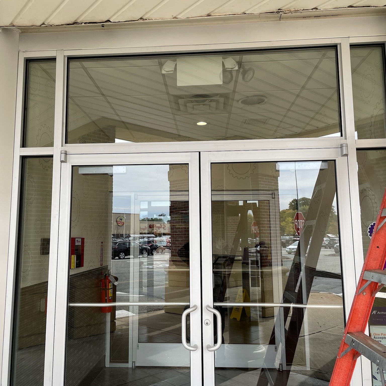 A red ladder sits in front of a glass door