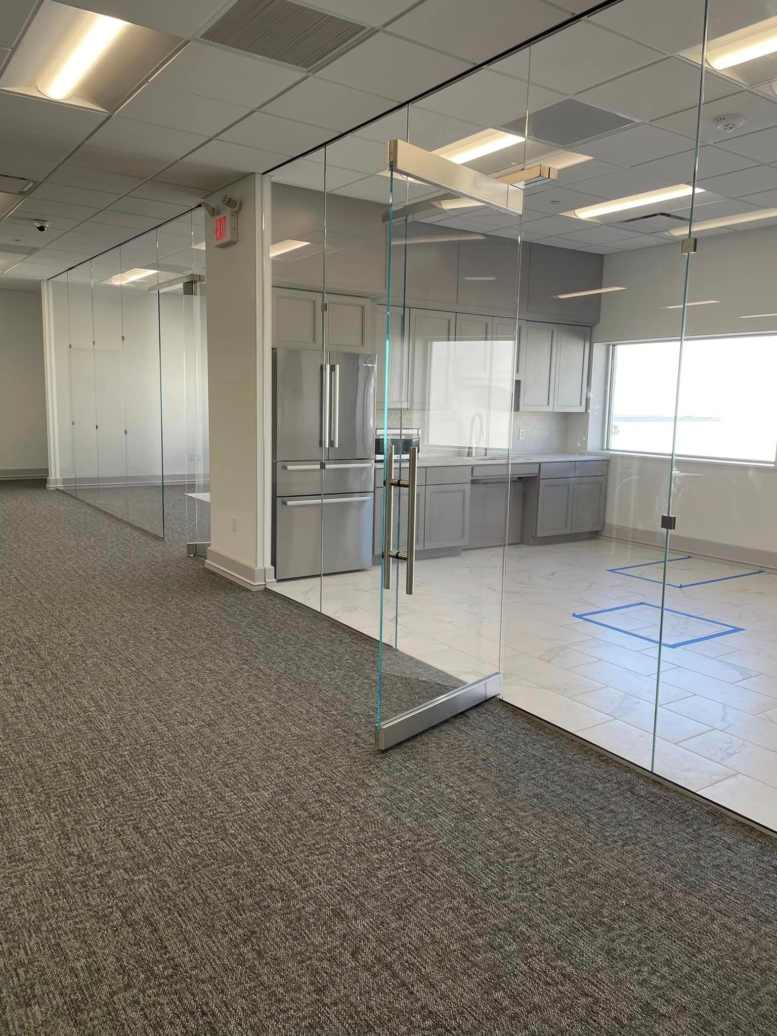 A large empty room with a refrigerator and a glass door.