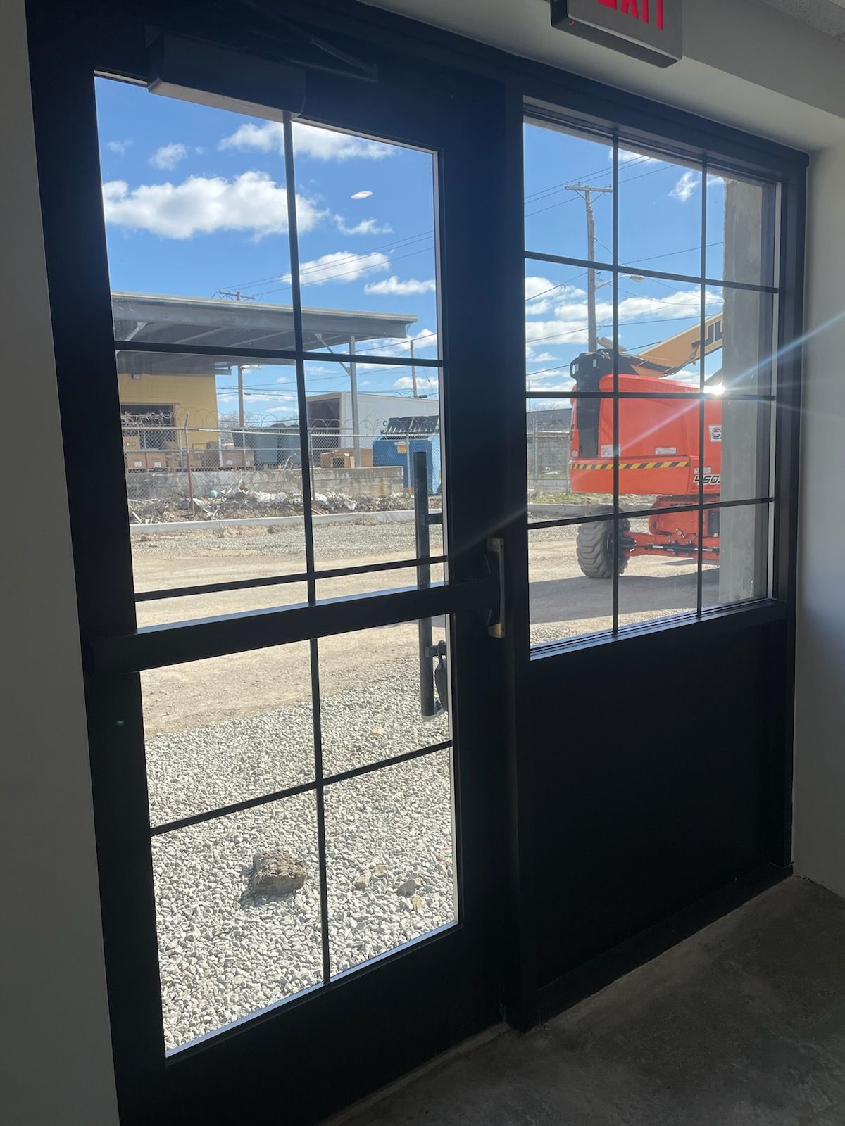 A black door with a lot of windows and a red truck in the background.