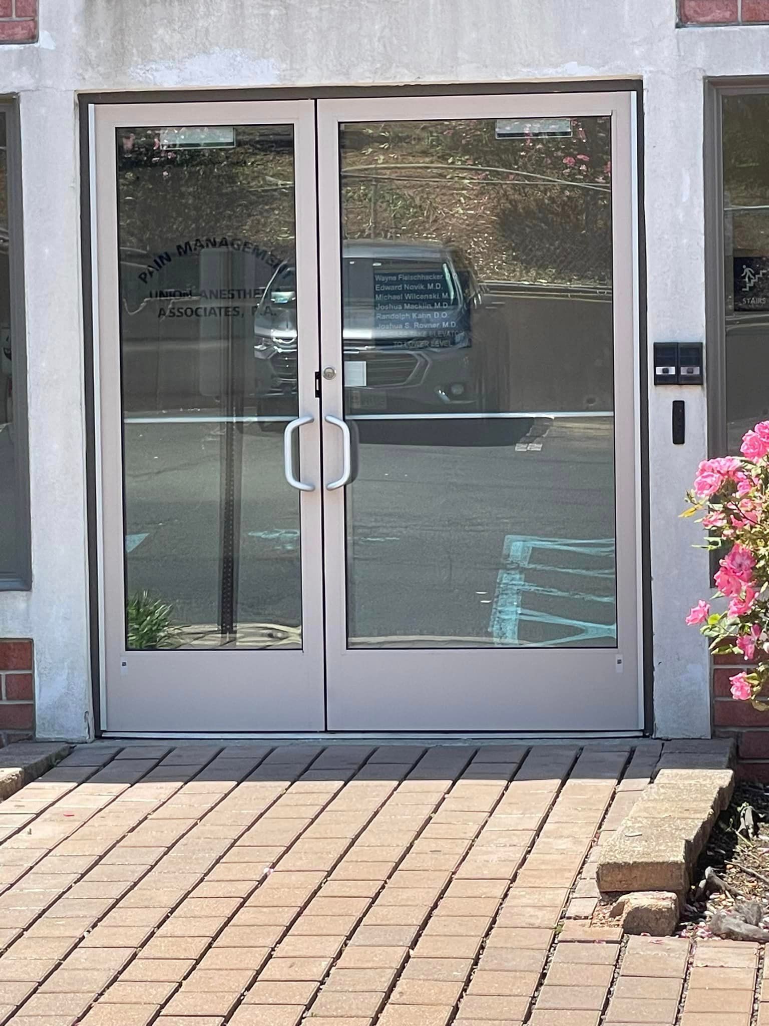 A pair of glass doors are sitting on a brick sidewalk.