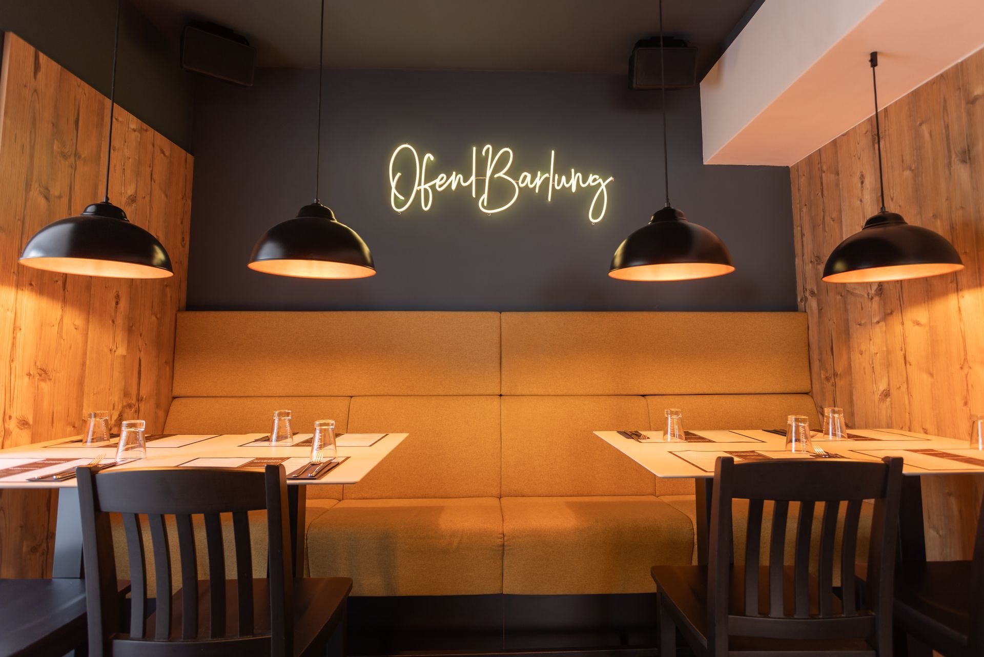 Ein Restaurant mit Tischen und Stühlen und einem Neonschild an der Wand