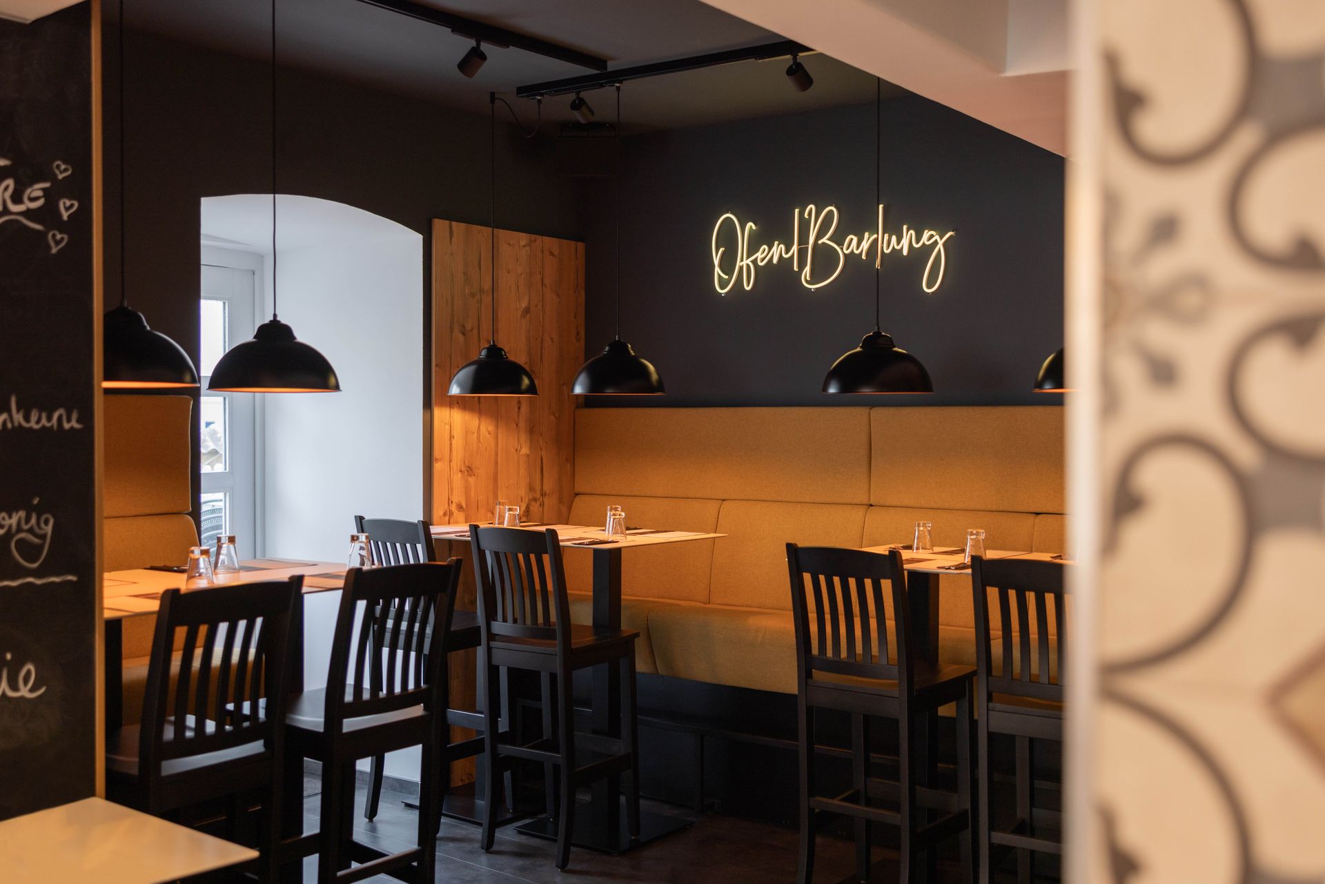 Ein Restaurant mit Tischen und Stühlen und einer Neonreklame an der Wand.