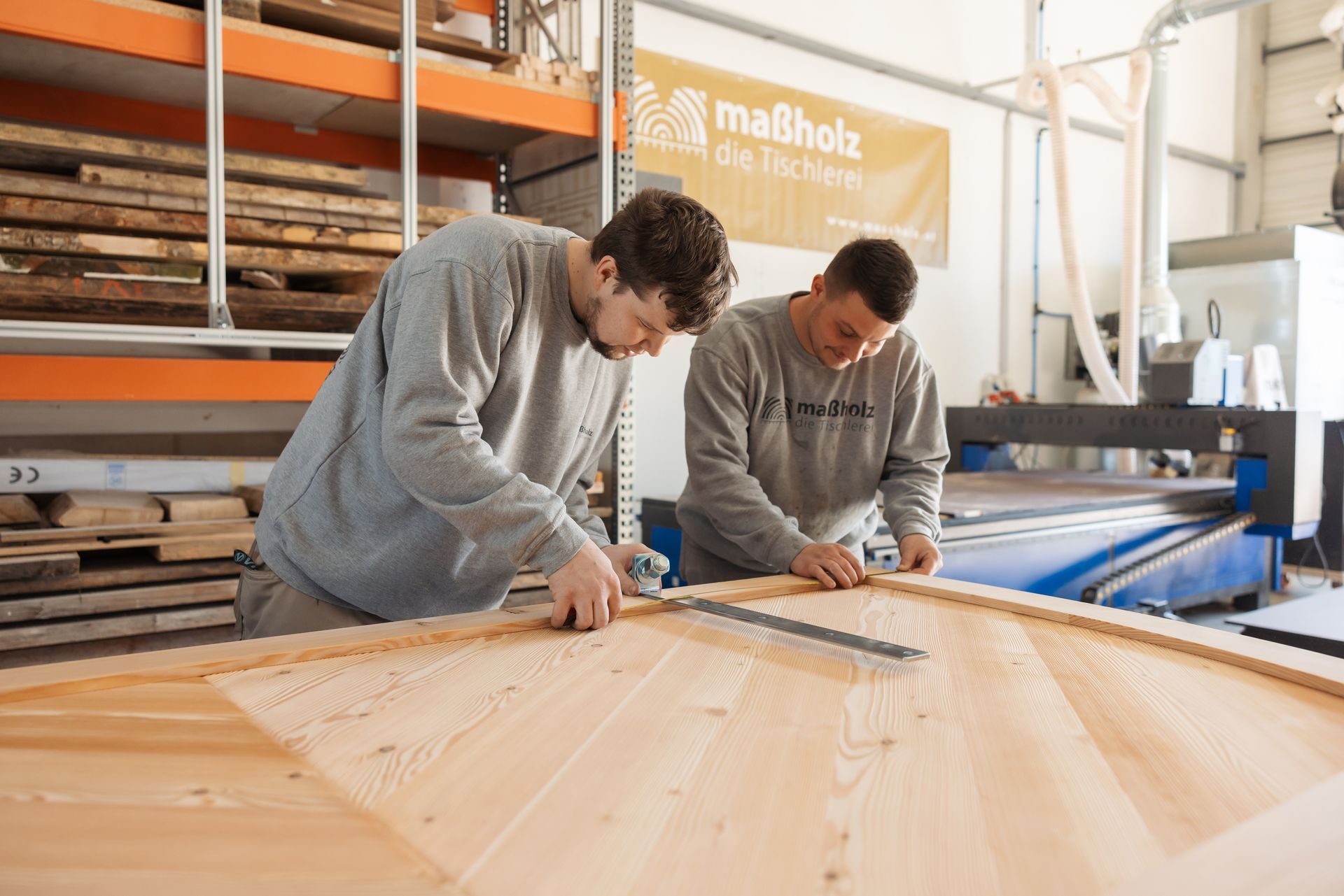 Zwei Männer arbeiten in einer Fabrik an einem Stück Holz.