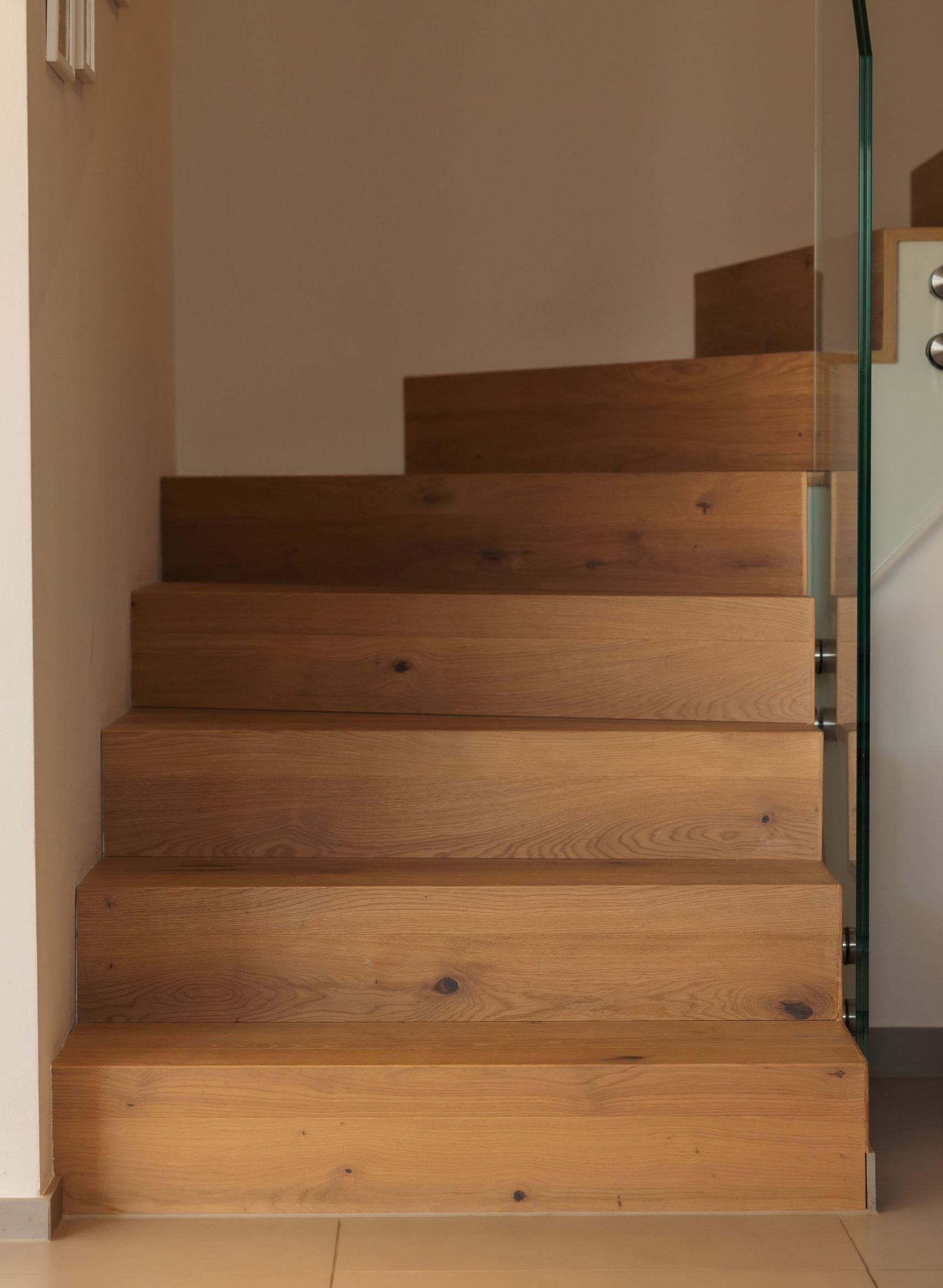 Eine Holztreppe mit einem Glasgeländer in einem Raum.