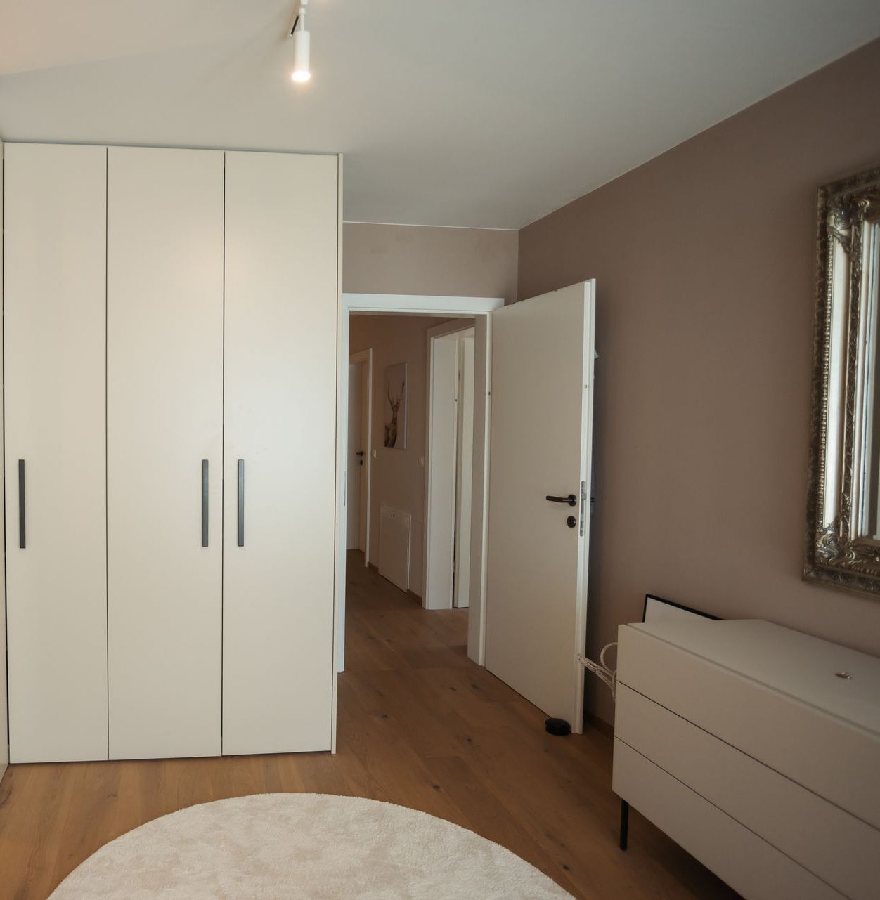 Ein Zimmer mit einer Kommode und einem Spiegel an der Wand