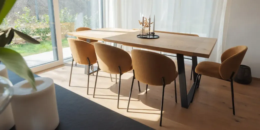 Ein Esszimmer mit Tisch und Stühlen vor einem großen Fenster.