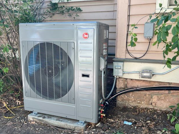 Close-up of an air conditioning unit with a gray fan and metal casing.
