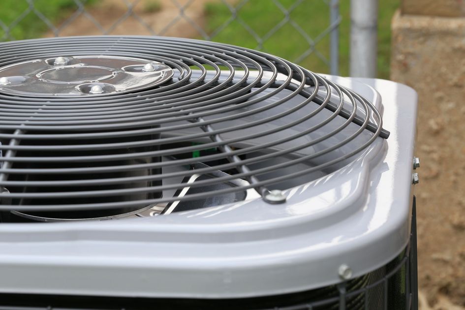 Close-up of an air conditioning unit with a gray fan and metal casing.