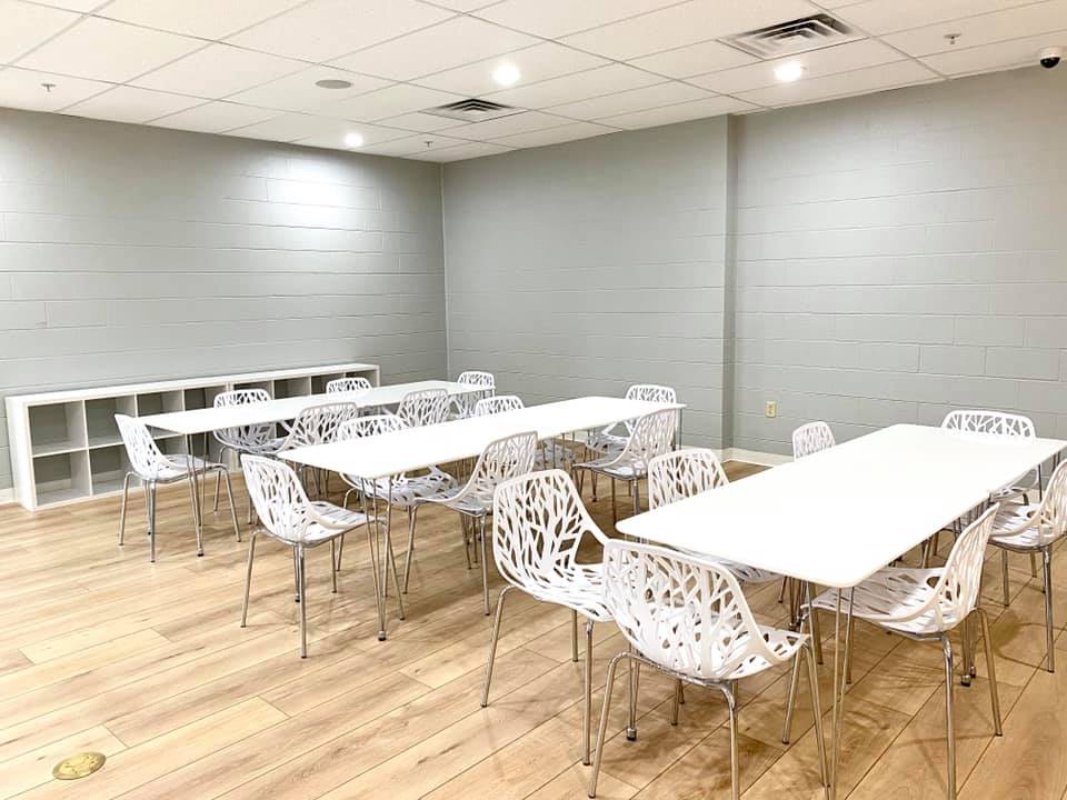 Empty modern conference room with white tables, patterned chairs, gray walls, and wood flooring